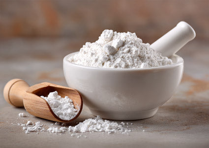 L-Alanine white powder in a bowl with a wooden scoop on a textured surface