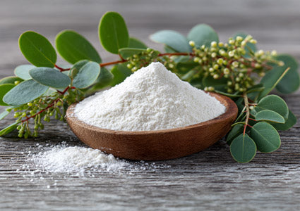 L-Lysine white powder in a wooden bowl with green leaves on a wooden surface