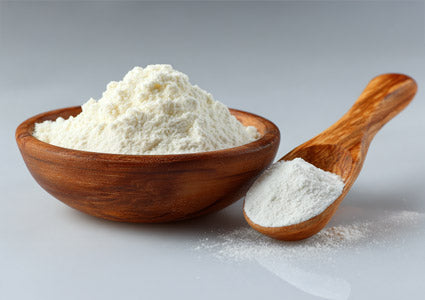 L-Methionine in a wooden bowl and spoon filled with white flour on a gray background