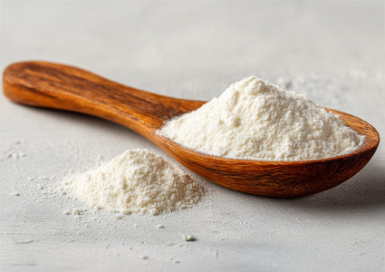 Wooden spoon filled with Taurine white powder on a light gray surface