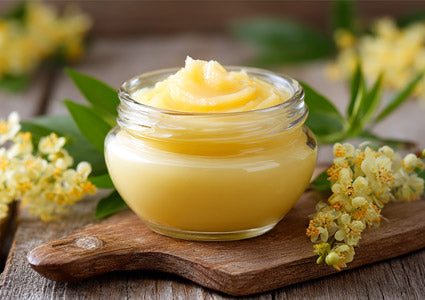 Jar of D3 yellow cream on a wooden board with flowers in the background