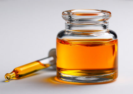 Estrofied Oil in Glass jar with amber liquid and dropper on a light gray background