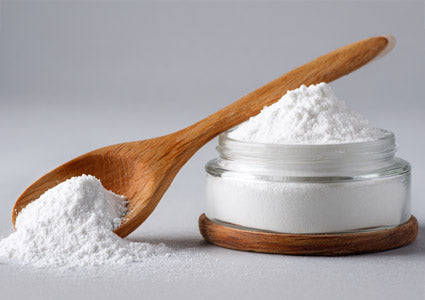 Wooden spoon and container filled with hyluanic acid white powder on a light gray background