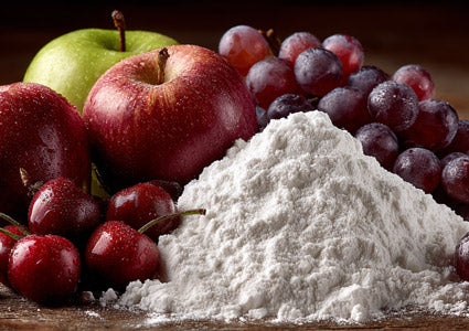 Malic Acid represented in white powder on a wooden surface with red apples, green apple, and red grapes.