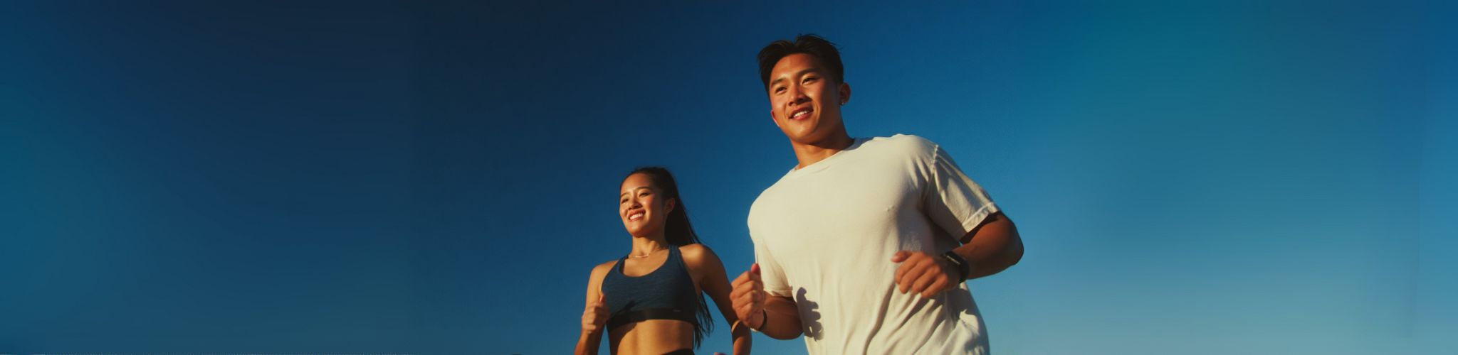 Two people running together against a clear blue sky